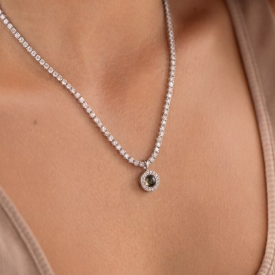 Close-up of a diamond-studded necklace with a round pendant resting on bare skin.